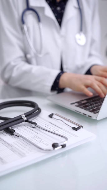 istock Stethoscope is lying on the glass table while doctor woman is working with laptop computer on the background, close-up. Medicine and pharmacy concept 2178755012