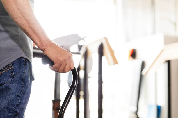 The unrecognizable male uses a walking cane during his therapy appointment for his physical therapy regimen.