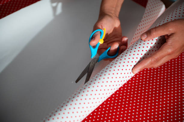 istock Hands meticulously cutting festive wrapping paper with scissors on a table, enhancing gift preparation for holiday celebrations 2178764980