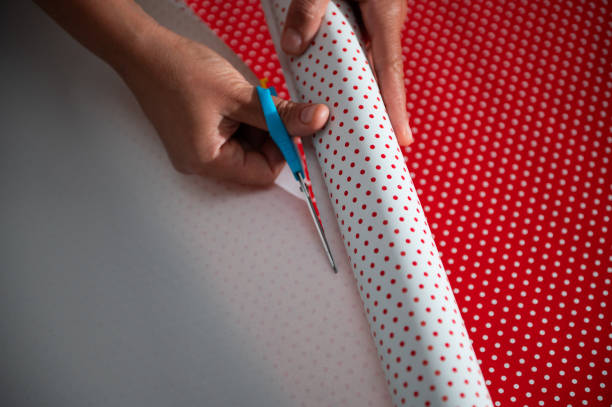 istock Hands cutting red and white polka dot wrapping paper during a DIY project. Focus on creativity, precision, and festive preparation, emphasizing the personal touch in gift wrapping. 2178764984