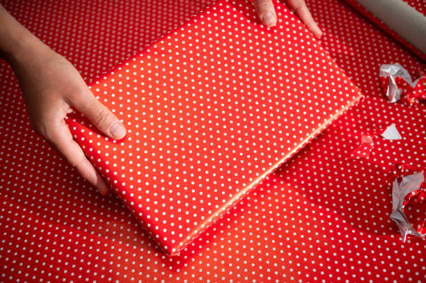 istock Hands holding a beautifully wrapped gift in vibrant red polka dot paper ready for a special occasion or holiday celebration 2178765012