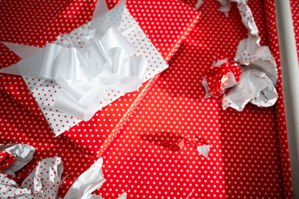 Brightly wrapped gifts in red polka dot paper with white ribbons evoke festive holiday cheer. Scattered wrapping paper adds a touch of fun and excitement to the celebratory scene.
