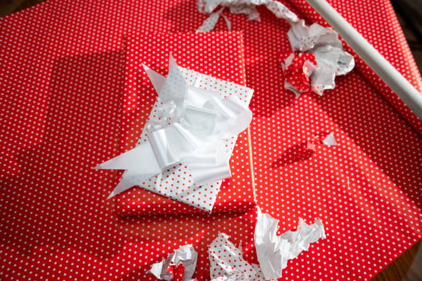 istock Beautifully wrapped gift with red polka dot wrapping paper and white bow surrounded by torn paper hints at joyous celebrations and thoughtful present exchanges. 2178765037