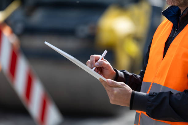 istock Construction worker taking notes while monitoring site activities at a busy road construction area during daylight 2178770315