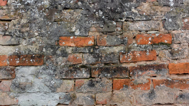istock Textured Brick Wall With Weathered Surfaces and Mossy Patches in Urban Setting 2178771580
