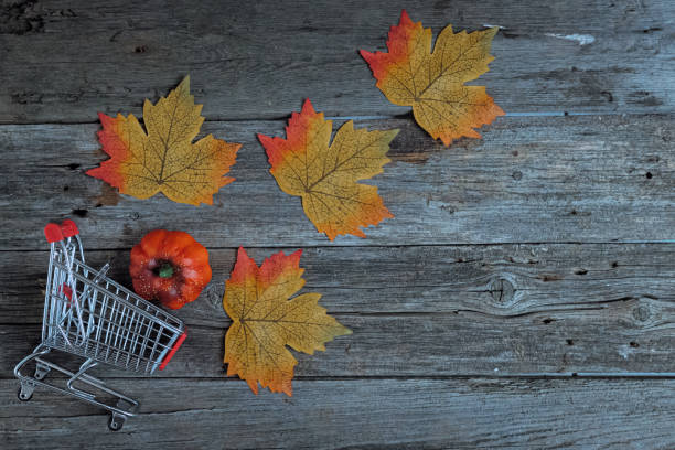 istock Shopping cart with falling maple leaves on the table. 2178775726