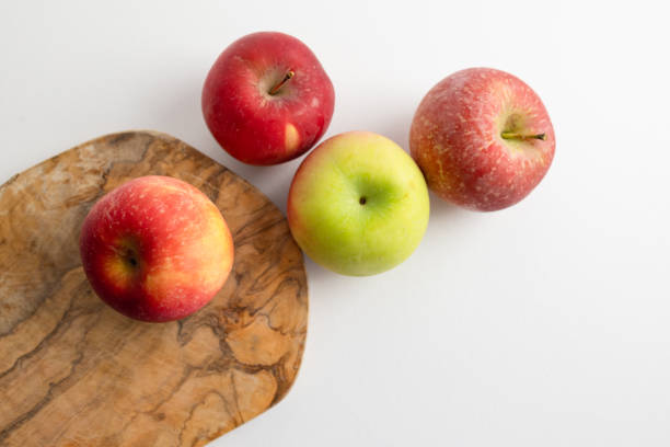 Organic unwashed apples on a cutting board on a white kitchen counter.