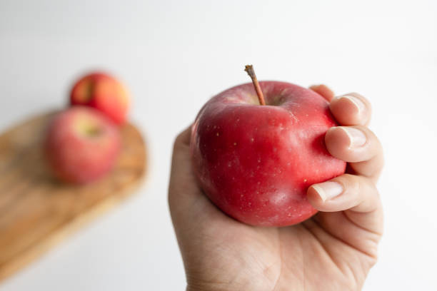 Organic unwashed apples on a cutting board on a white kitchen counter.