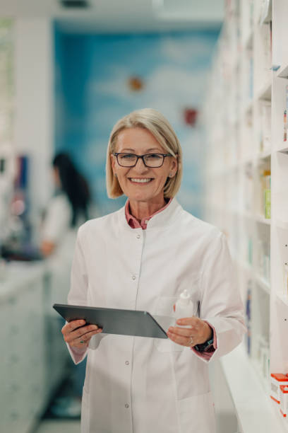 istock Senior female pharmacist holding nasal spray and using digital tablet in a pharmacy 2178779116
