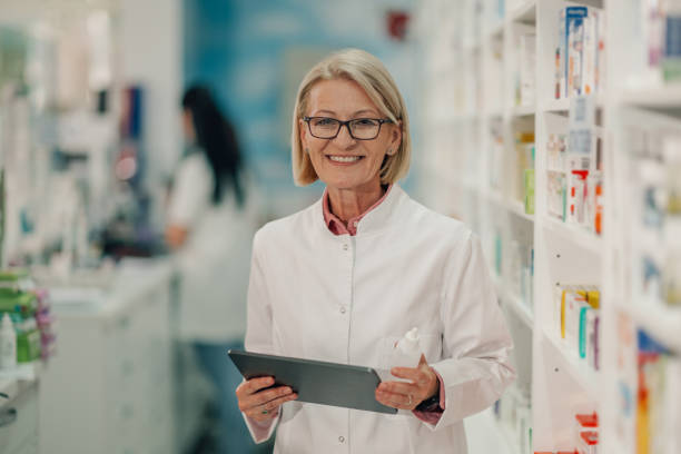 istock Senior female pharmacist holding medication and using digital tablet in pharmacy 2178779122