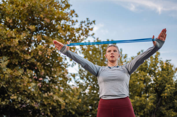 Young woman stretching resistance band outdoors in a park