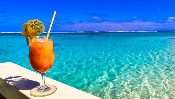 istock Vibrant cocktail with tropical garnish adorns railing overlooking Cook Islands lagoon, swimmers and distant reef create idyllic vacation moment. Crystal-clear water and vibrant colors offer 2178797595