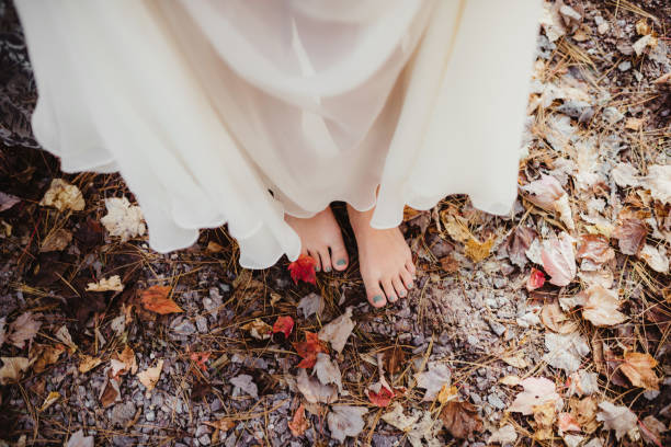 Bride in wedding dress and boho bare toes walking in autumn