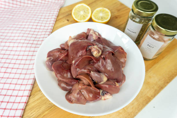 Fresh chicken liver at white bowl on a cutting board with cooking ingredients