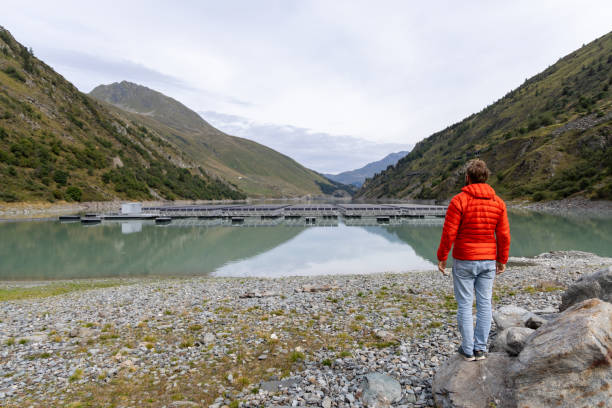 istock Person Standing by a Mountain Reservoir with Floating Solar Panels 2178816868