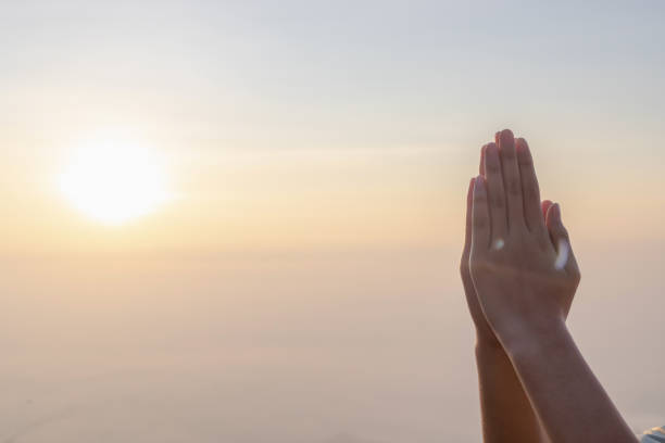 istock Hands placed together praying in morning sunrise sky background.. 2178819351