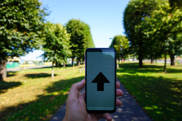 Cropped hand holding a mobile phone with a arrow on the screen