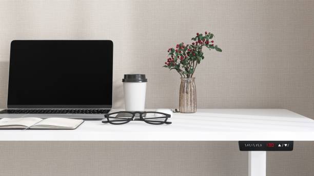 istock Desktop of modern white stand up desk with laptop computer, smartphone, earphone, notebook and eyeglasses in sunlight from window on beige wall for home office working, product background 3D 2178828714