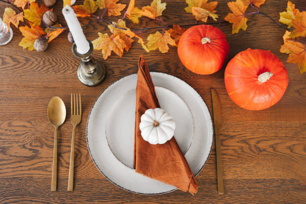 istock Autumn dinner table setting for holiday with pumpkins, cutlery, and warm fall decorations, top view 2178828873