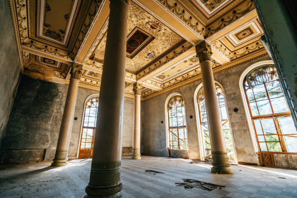 istock Empty, decaying ballroom featuring tall columns, arched windows, and intricate ceiling designs in historic, abandoned building 2178829649
