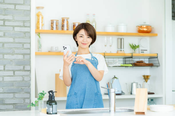 istock Smiling woman with smartphone in the kitchen 2178830636