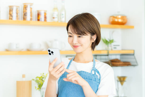 istock Smiling woman with smartphone in the kitchen 2178830648
