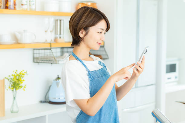 istock Smiling woman with smartphone in the kitchen 2178830845