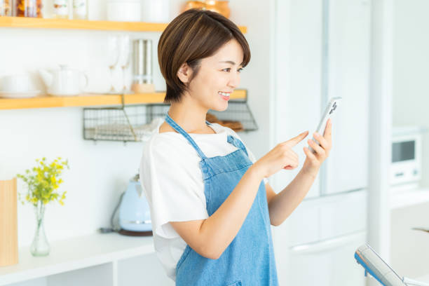 istock Smiling woman with smartphone in the kitchen 2178830852