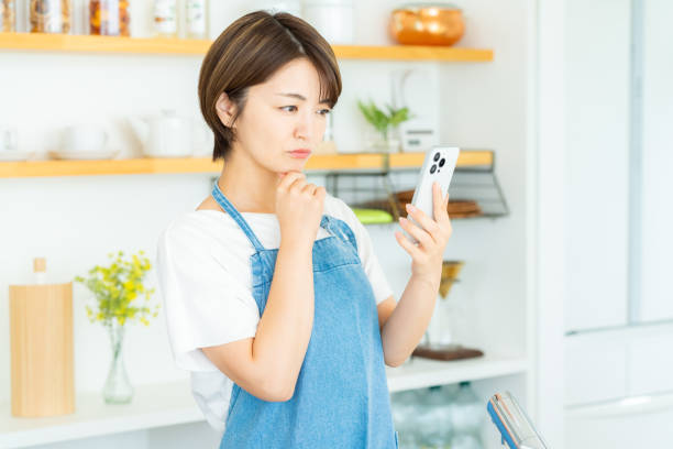 istock Smiling woman with smartphone in the kitchen 2178831169