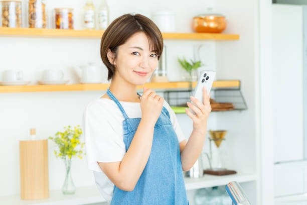 istock Smiling woman with smartphone in the kitchen 2178831180