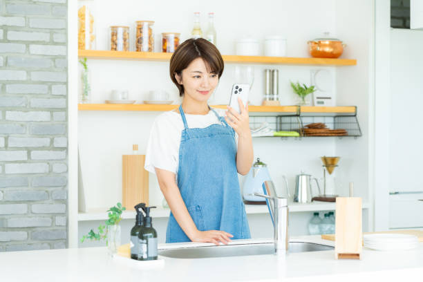 istock Smiling woman with smartphone in the kitchen 2178831181