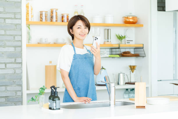 istock Smiling woman with smartphone in the kitchen 2178831188