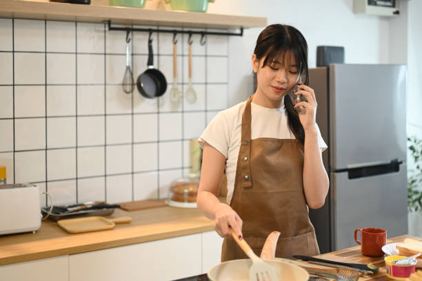 istock Attractive young woman cooking on kitchen counter while talking on cellphone 2178831951