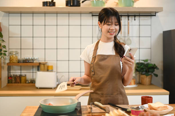 istock Smiling young woman using smartphone while preparing meal on a wooden worktop 2178831954