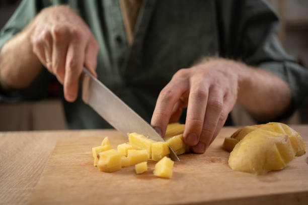 istock male hands cutting potatoes on wooden board. 2178832117