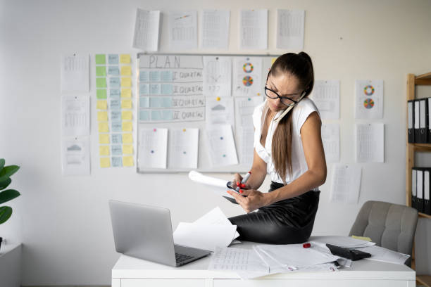 istock Multitasking intelligent accountant woman call on smartphone use wireless laptop project business center and writing notes in clipboard working in office 2178832216