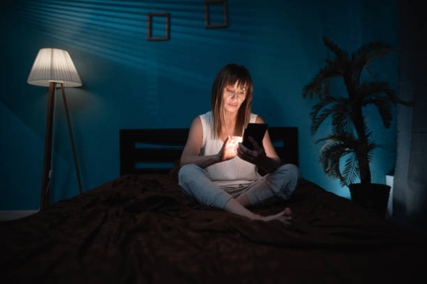 istock Sleepy exhausted lady lying in bed using smartphone. Sad woman using mobile phone late at night in dark bedroom 2178832319