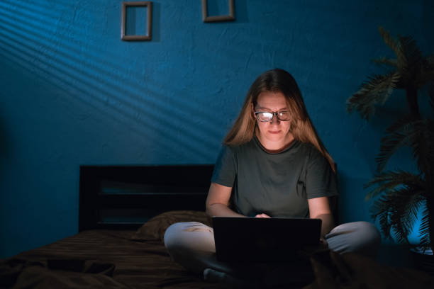 istock Focused caucasian woman in glasses looking at laptop screen while working on project until night, in bed with pc. lady freelancer studying or working at night to meet deadlines 2178832389
