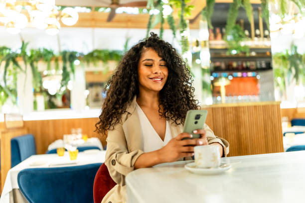 istock Beauty latin woman using mobile sitting on a cafeteria 2178837275