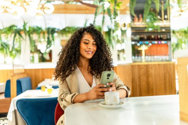 istock Smiling woman using date app sitting on a cafeteria 2178837298
