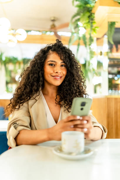 istock Chic beauty woman using phone sitting on a cafeteria 2178837307