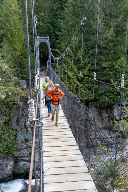 istock Guide and guests hike across suspension bridge over river 2178840309