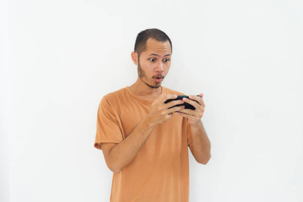 istock Young men wearing orange shirt is happy playing game using phone on isolated white background 2178840394
