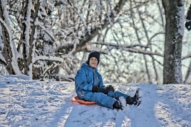 Boy sitting on a ski slider on a top of a hill during winter sunny day, Belgrade Serbia