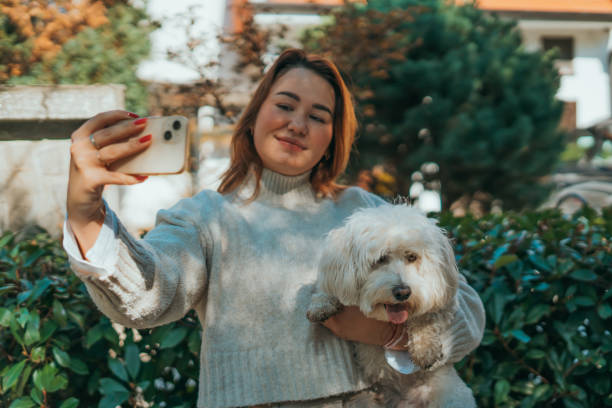 istock smiling young woman is taking a selfie with a white dog. 2178843521