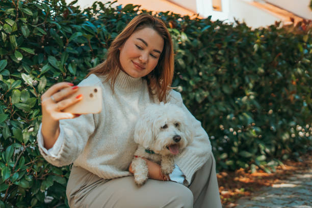 istock smiling young woman is taking a selfie with a white dog. 2178843523