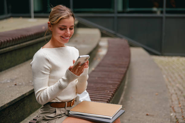 istock A young woman is actively engaged with her smartphone while enjoying an urban setting atmosphere 2178847876