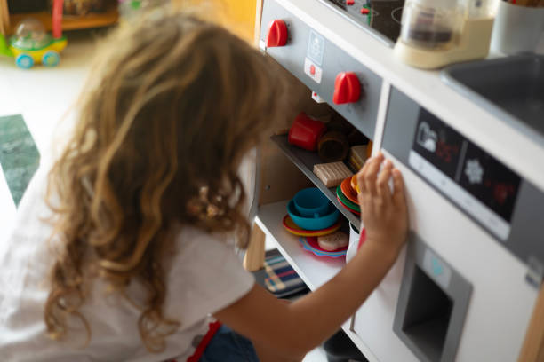istock Little girl exploring toy kitchen cabinets 2178848101