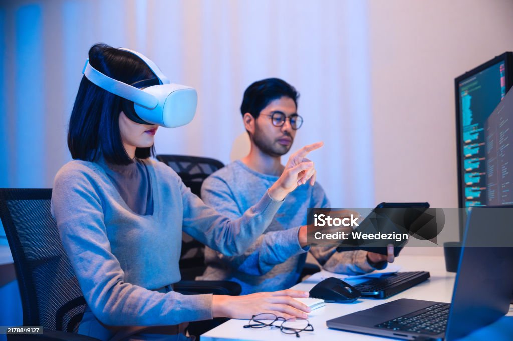 Asian Software Developer Wearing A Virtual Reality Headset Works On A ...