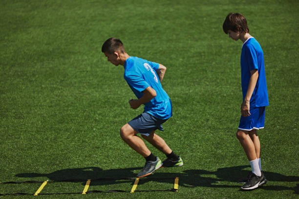 istock Agility Drill in Action. Two boys in blue jerseys concentrating on agility ladder drill, training, improving quickness and coordination. 2178851536